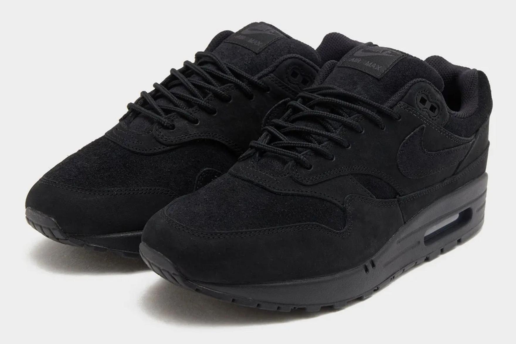 All-black Nike Air Max sneakers on grey background