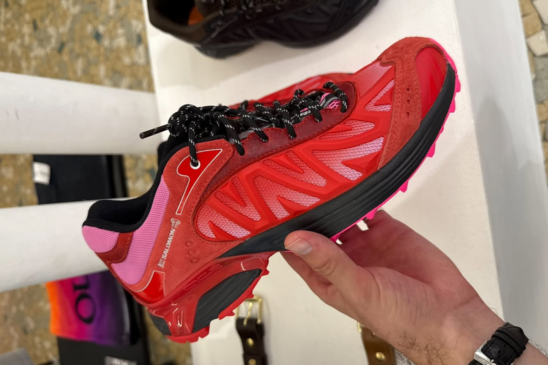 red salomon sneaker in hand shot