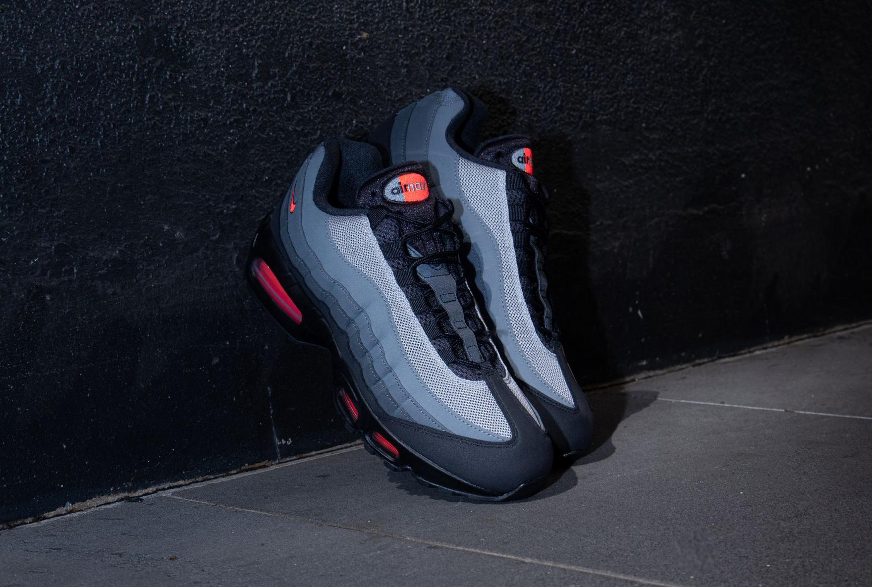 Nike Air Max 95 grey and red sneakers sitting against concrete wall