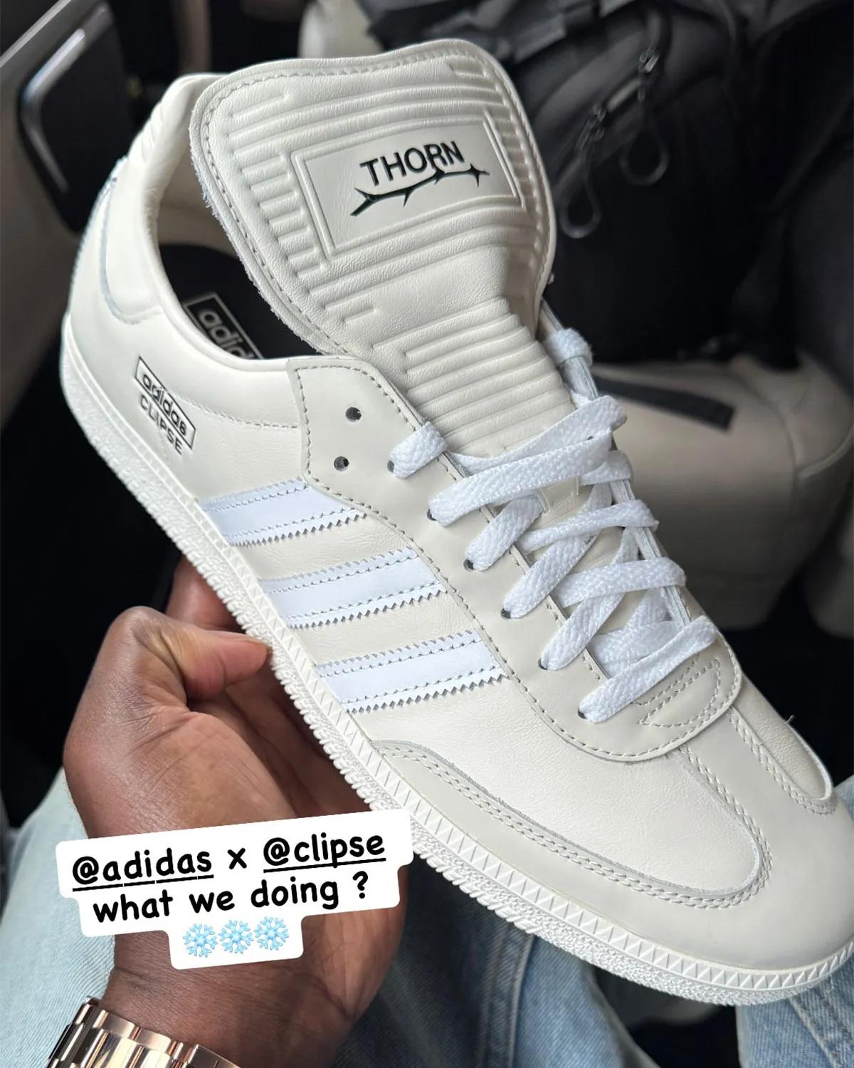 White adidas sneaker held in person's hand