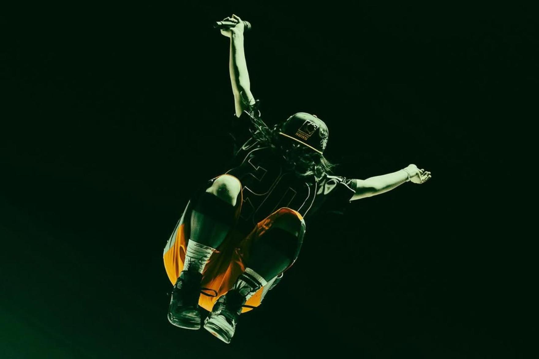 Singer Billie Eilish jumping in the air with sneakers on