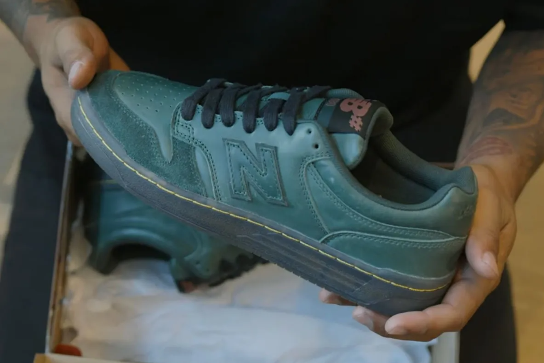 in-hand shot of green new balance sneaker held in a pair of hands