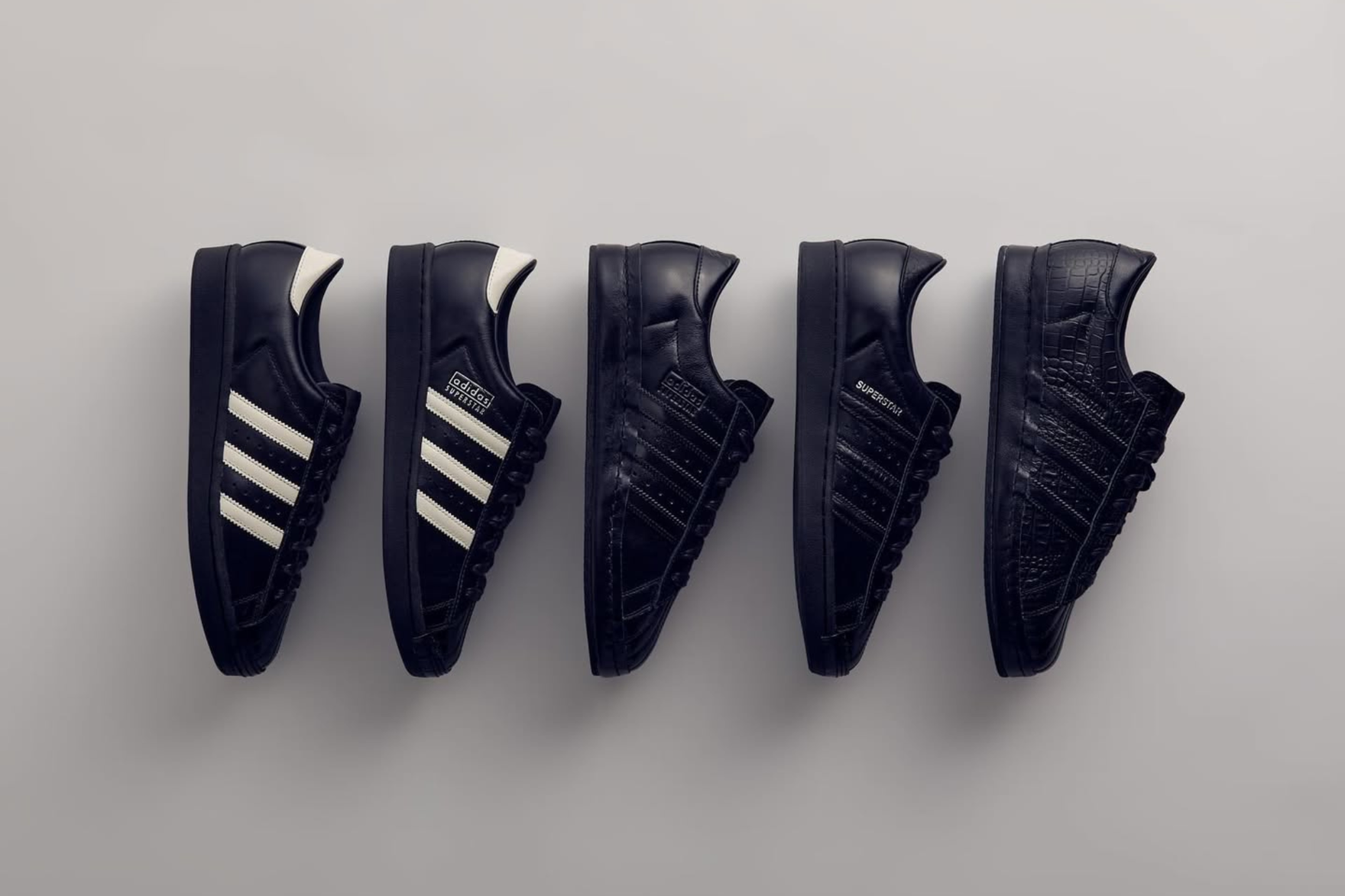 a line up of adidas superstar sneakers on grey background