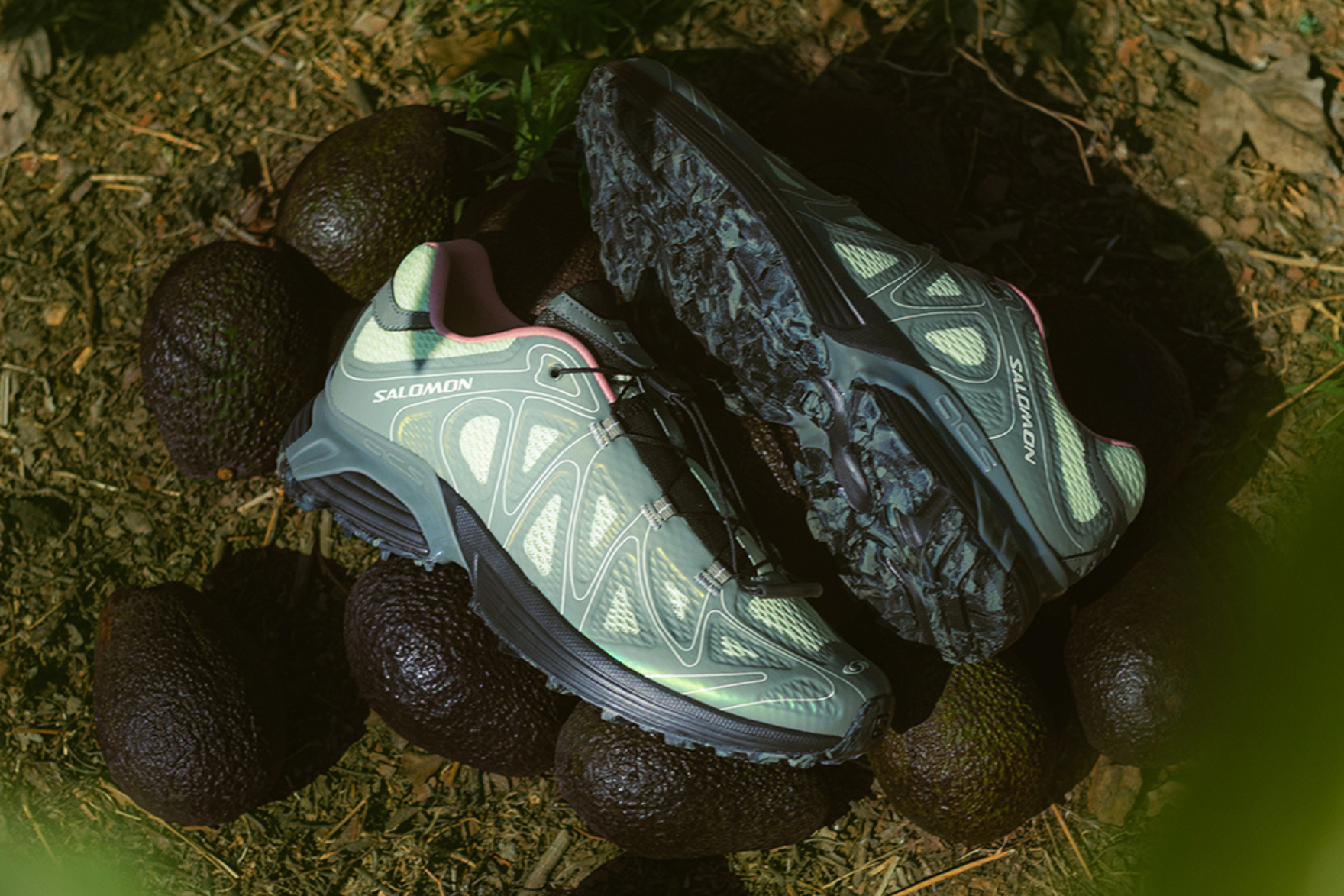 green coloured salomon sneaker laying next to some avocados