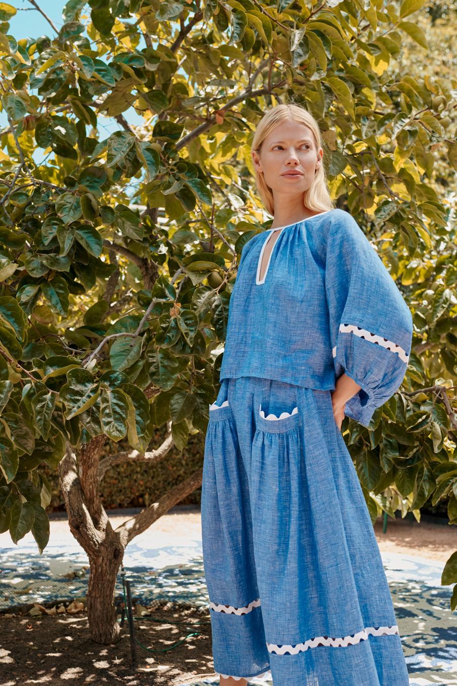 Blonde woman in blue dress next to tree