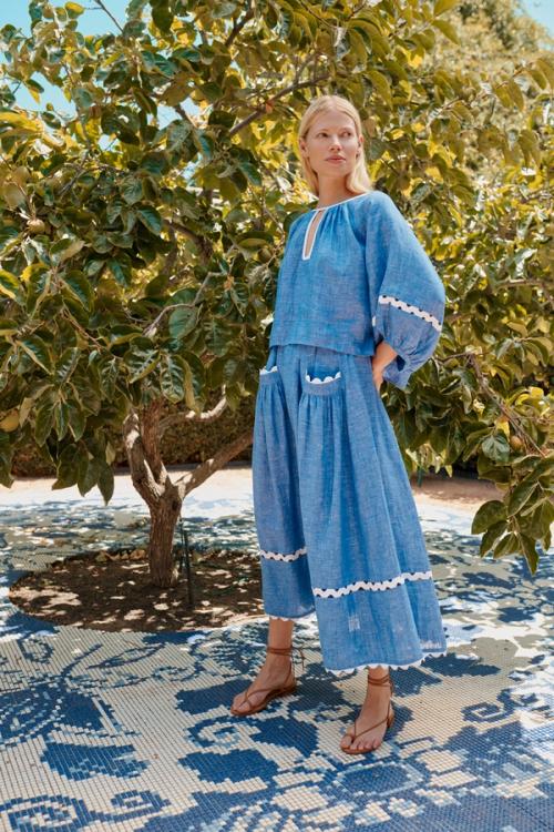 Blonde woman in blue dress next to tree