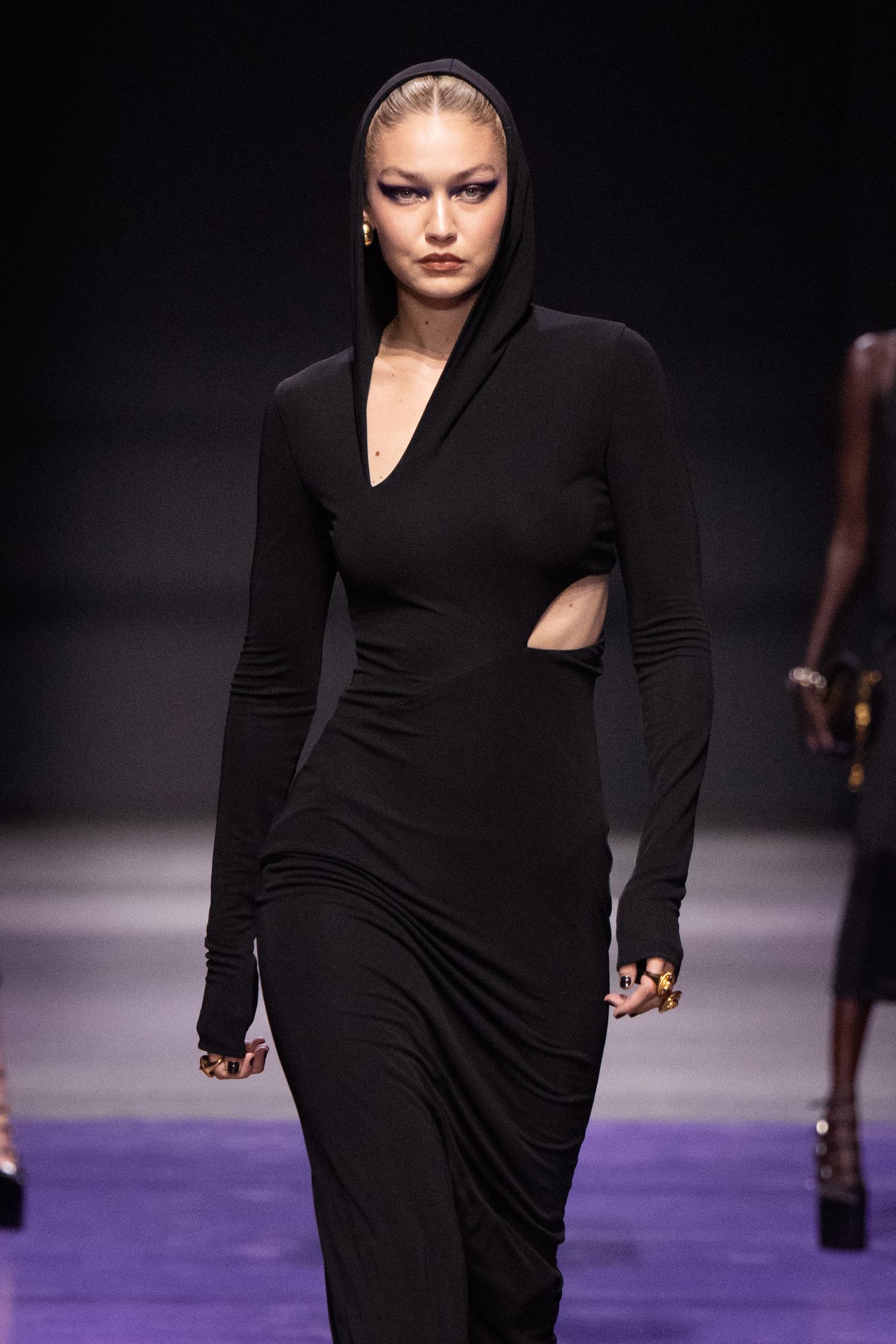 Gigi Hadid walking for Versace wearing a long black hooded dress