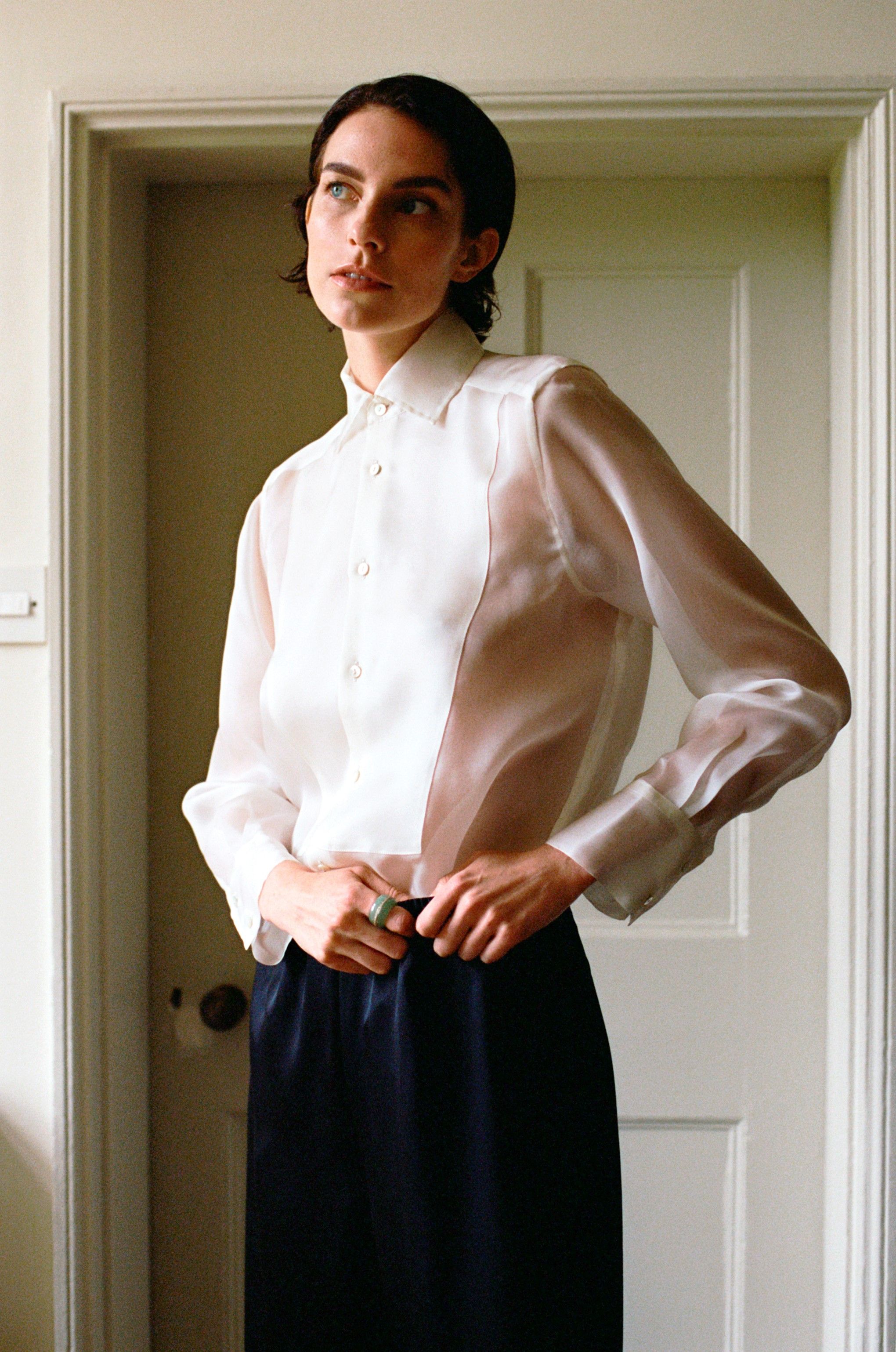 Woman with short dark hair wearing a sheer white shirt