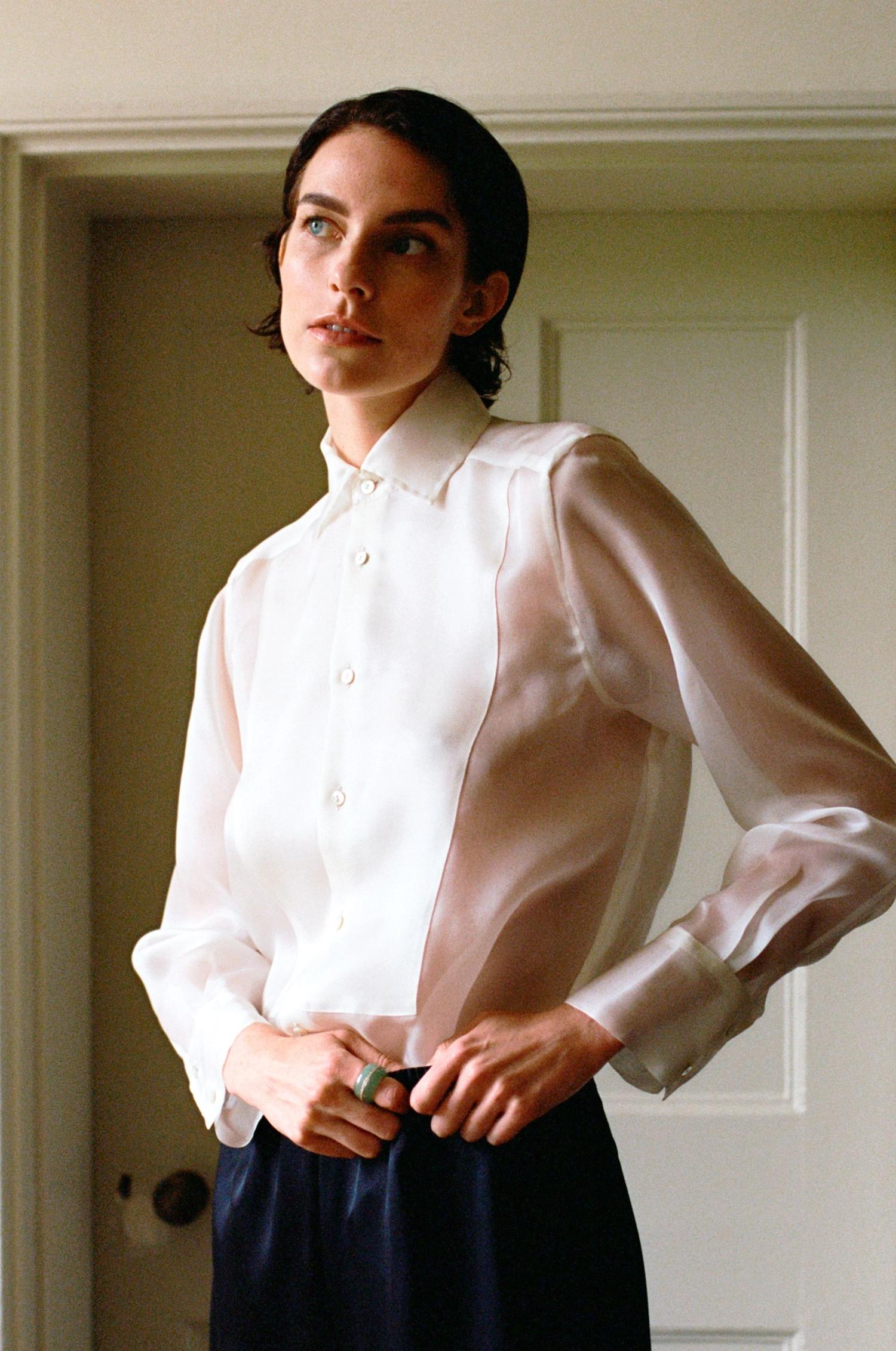 Woman with short dark hair wearing a sheer white shirt