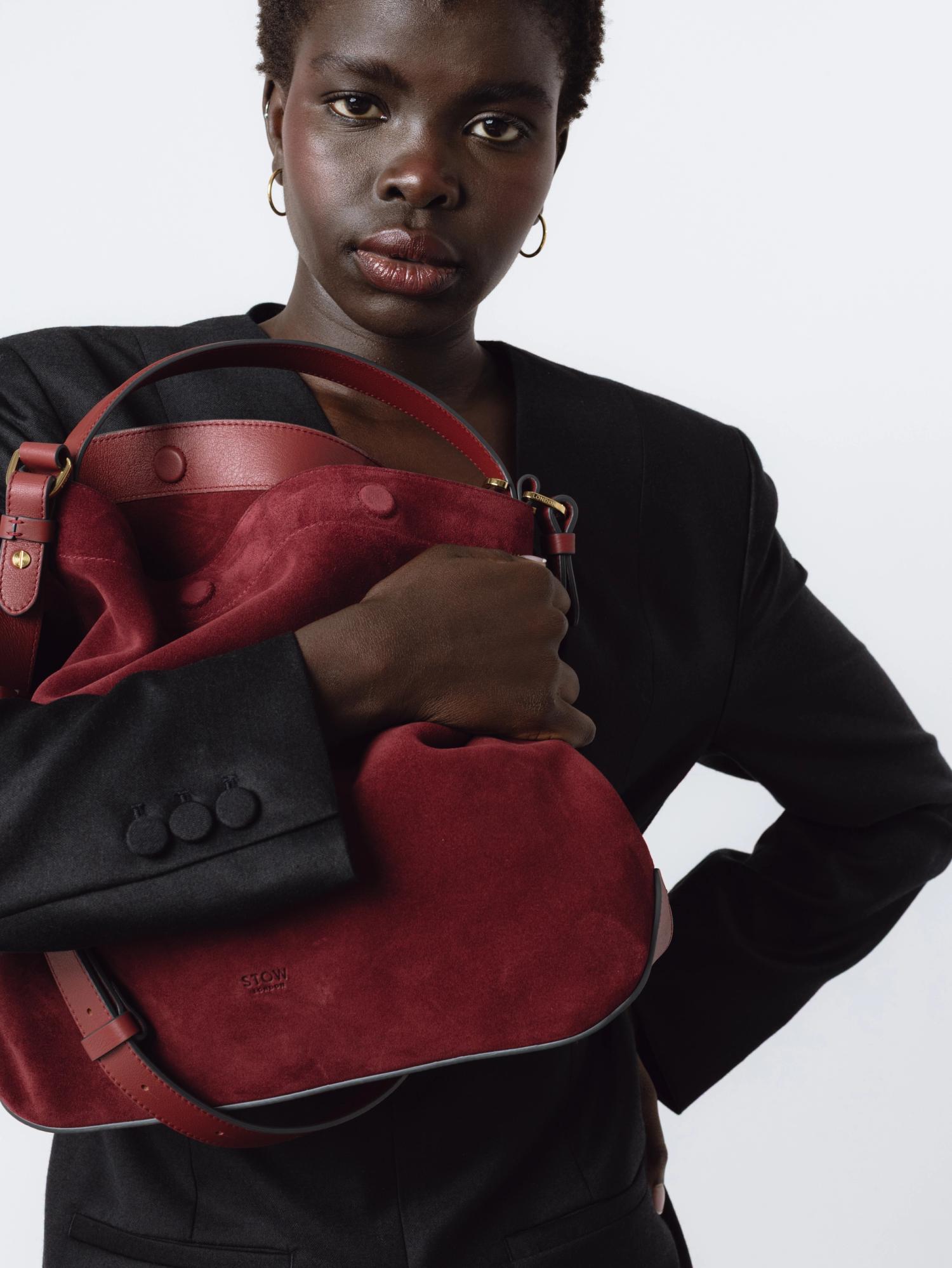 Woman dressed in black holding a red suede bag