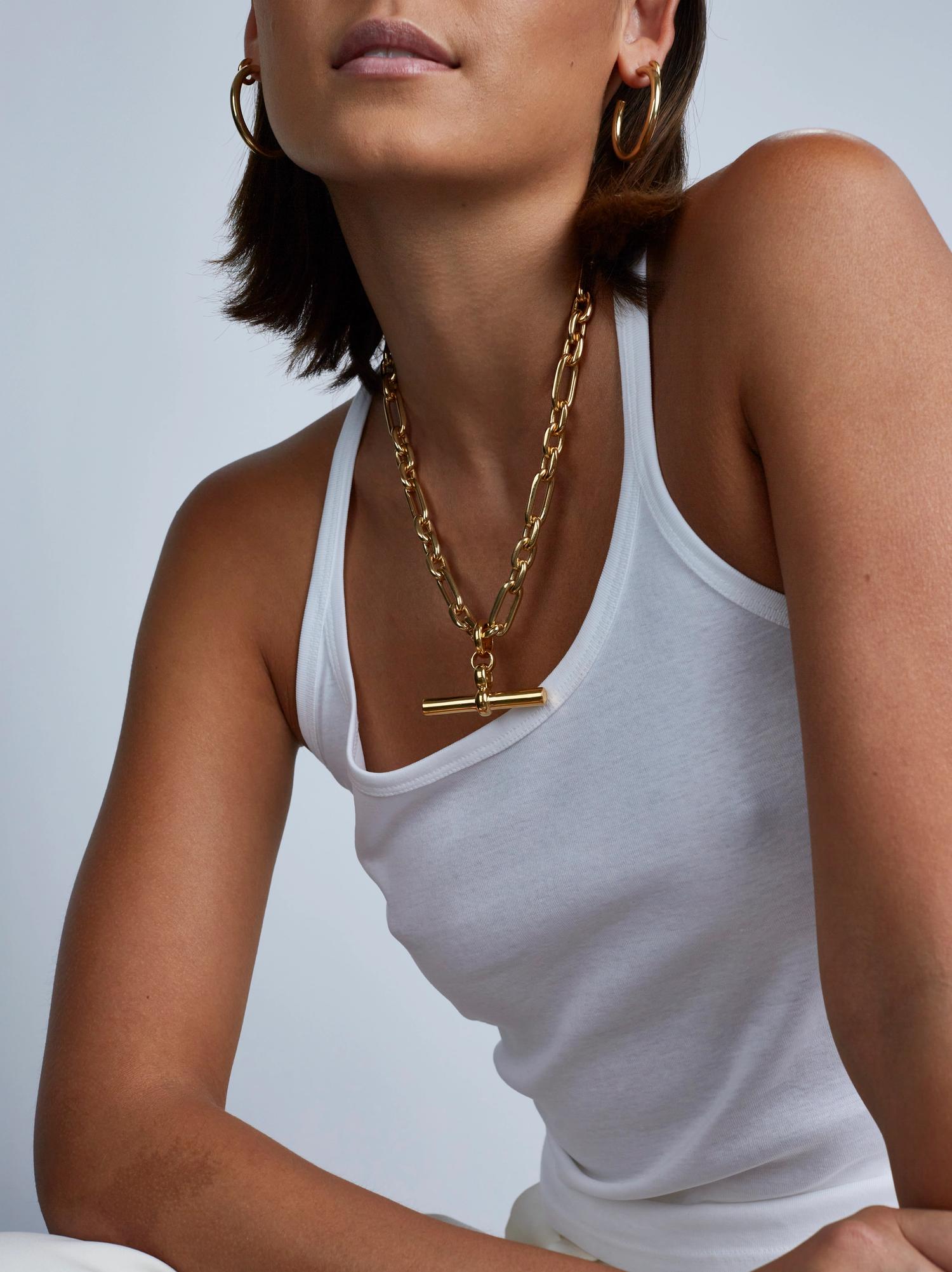Model wearing gold t bar necklace.