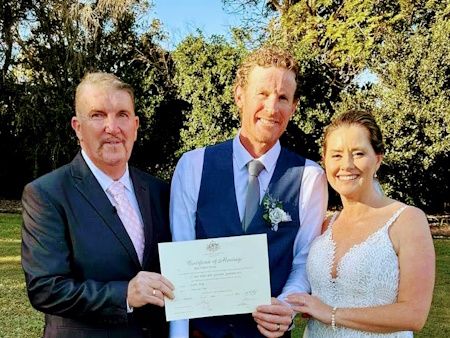 Mark and a couple presenting their commemorative marriage certificate