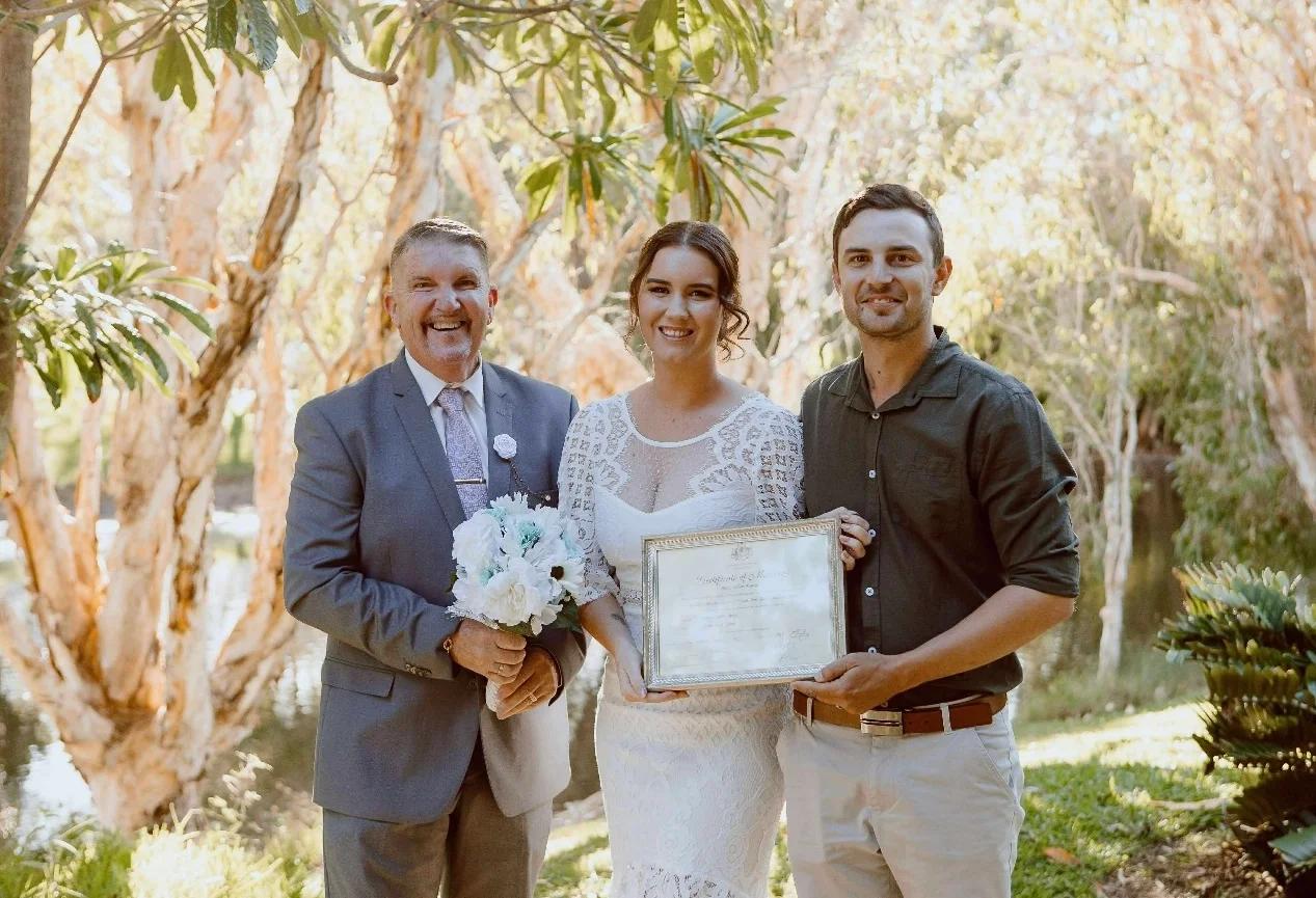 Mark with a couple holding their commemorative marriage certificate