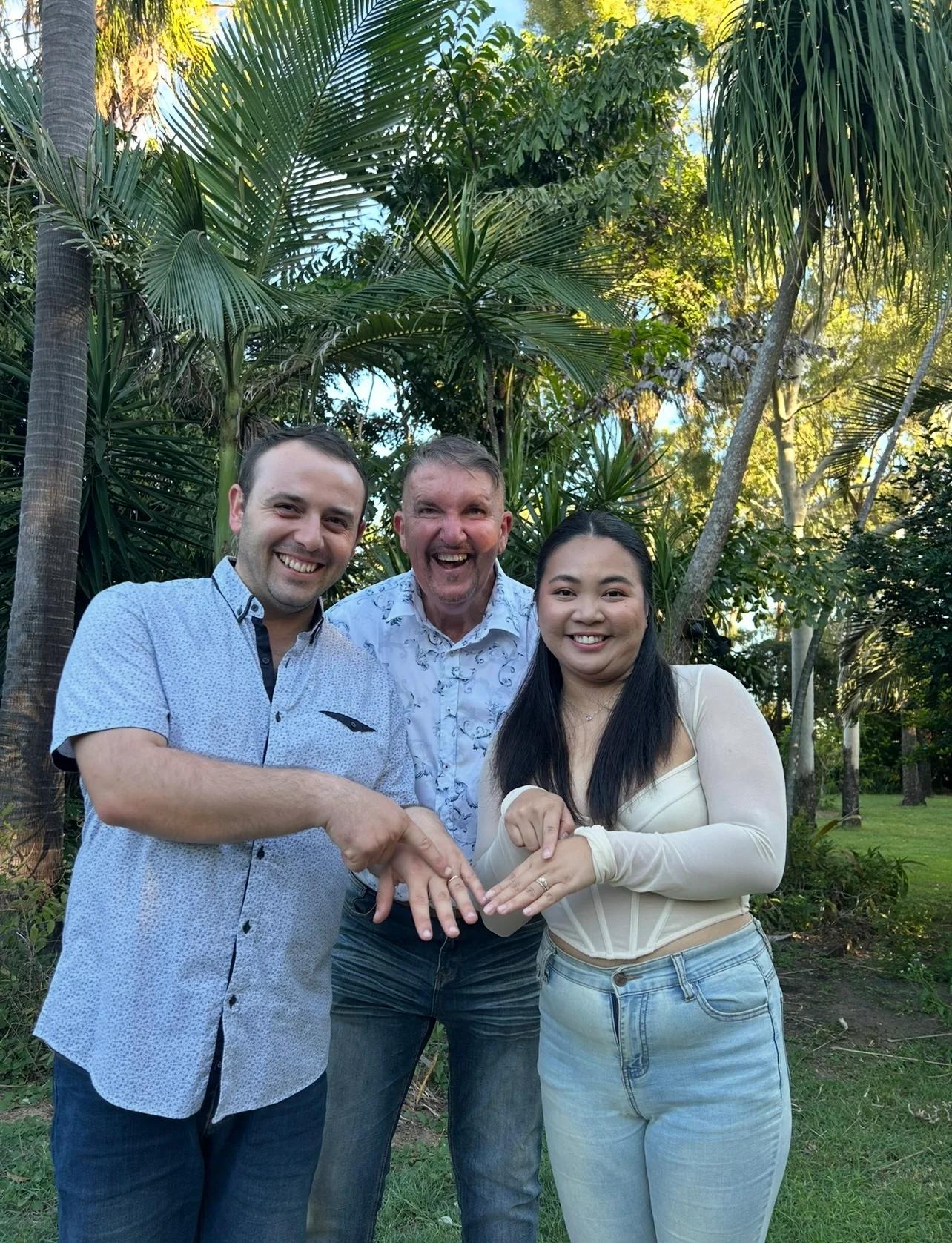 A smiling couple showing their rings with Mark