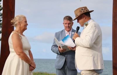 Mark listening as a couple exchange vows beside the water
