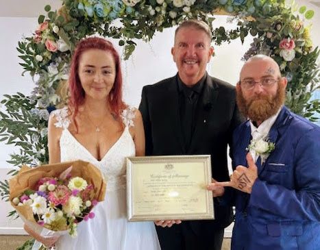 Mark with a couple holding their commemorative marriage certificate