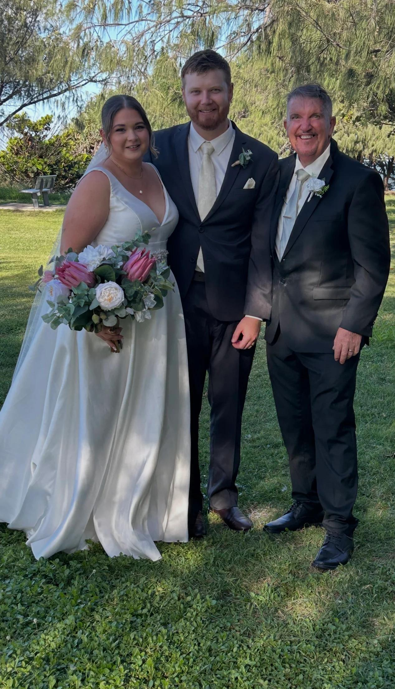 Mark standing with newlyweds in a leafy garden