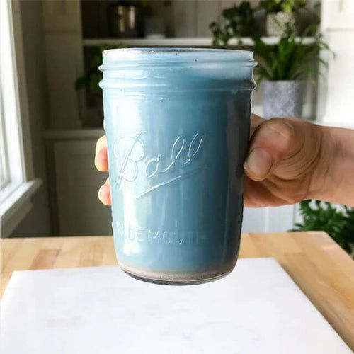 Blue Majik Almond Milk splashed in a glass, made with antioxidant-rich Blue Spirulina with Almond Cow