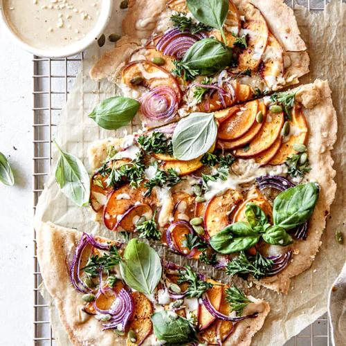 Pizza topped with basil and peaches and onion
