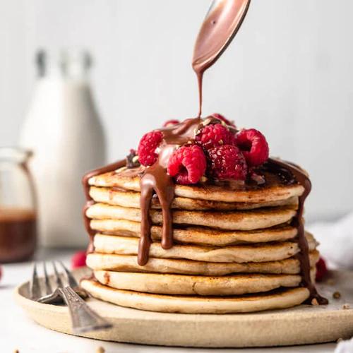 Gluten-free, dairy-free Coconoat Pulp Pancakes decorated with Homemade Hazelnut Nutella and fresh raspberries by Almond Cow