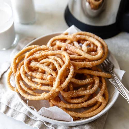 Funnel Cakes stacked on a plate and topped with powdered sugar