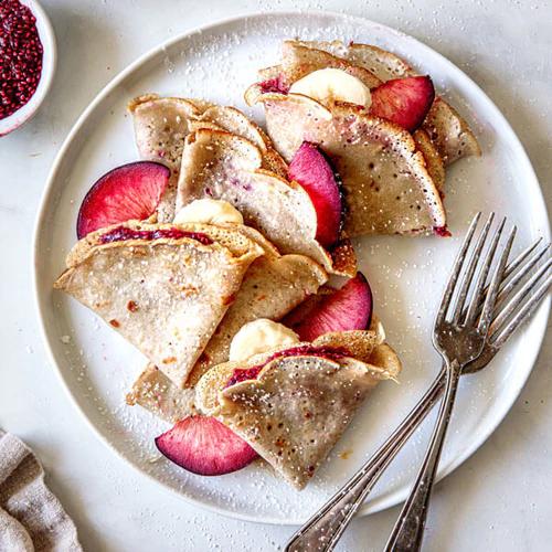 Almond Cow's Vegan & Gluten-Free Crepes garnished with fresh fruit and a sprinkle of powdered sugar