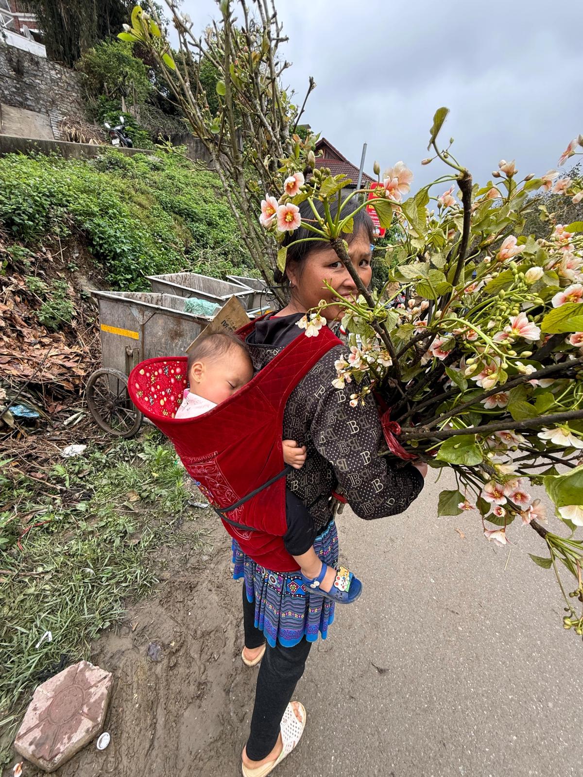 Vietnamese girl carries baby and flowers