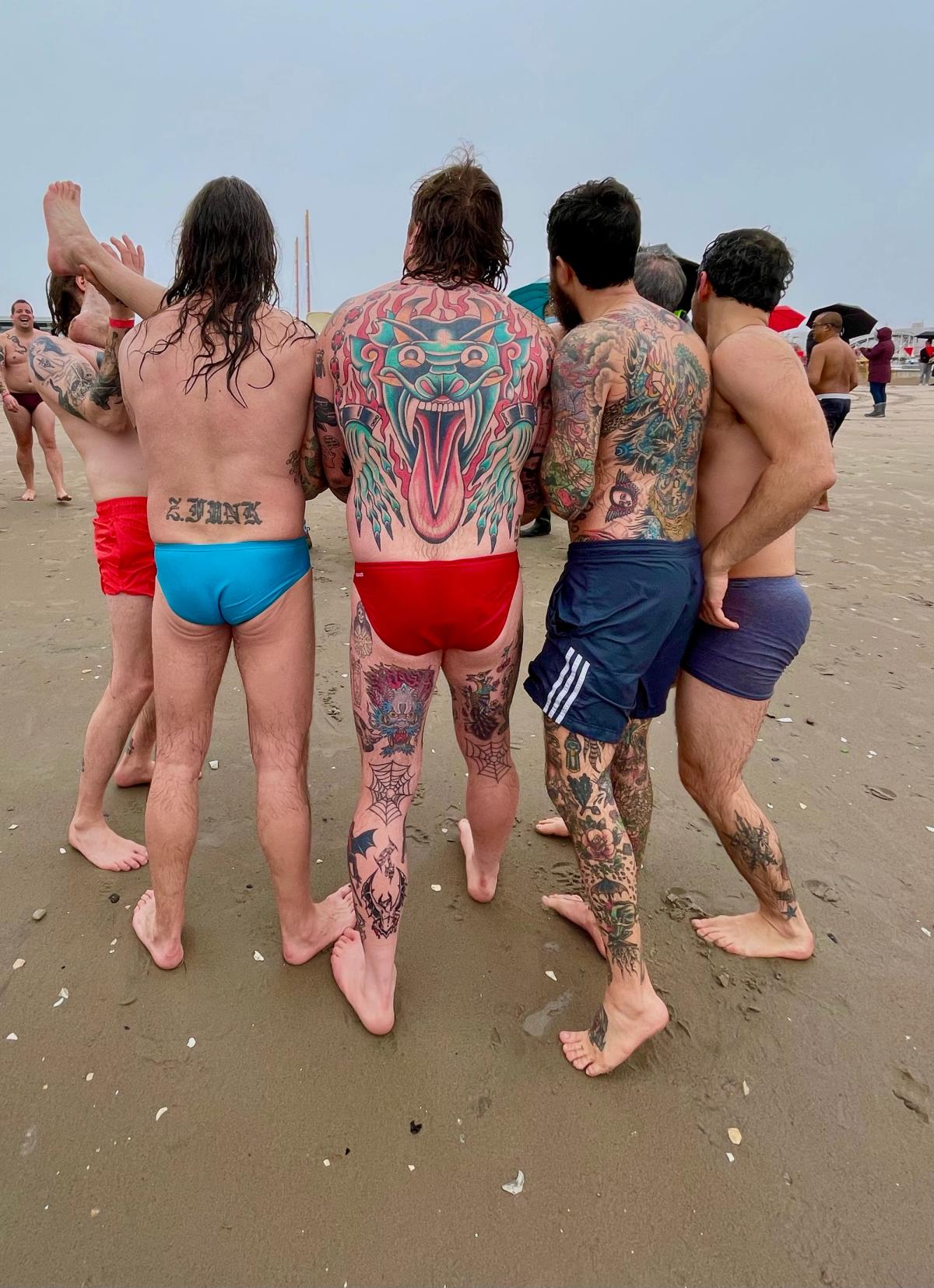 men backs w tattoos on coney island beach 
