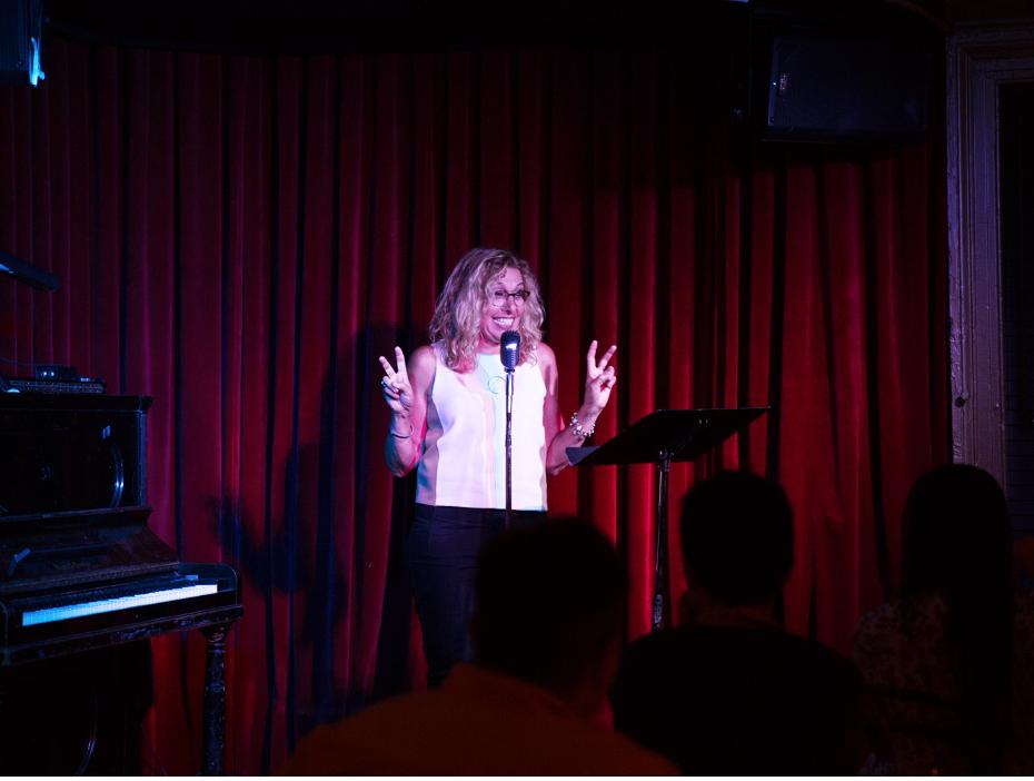 Woman standing on stage holding peace sign