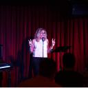 Woman standing on stage holding peace sign