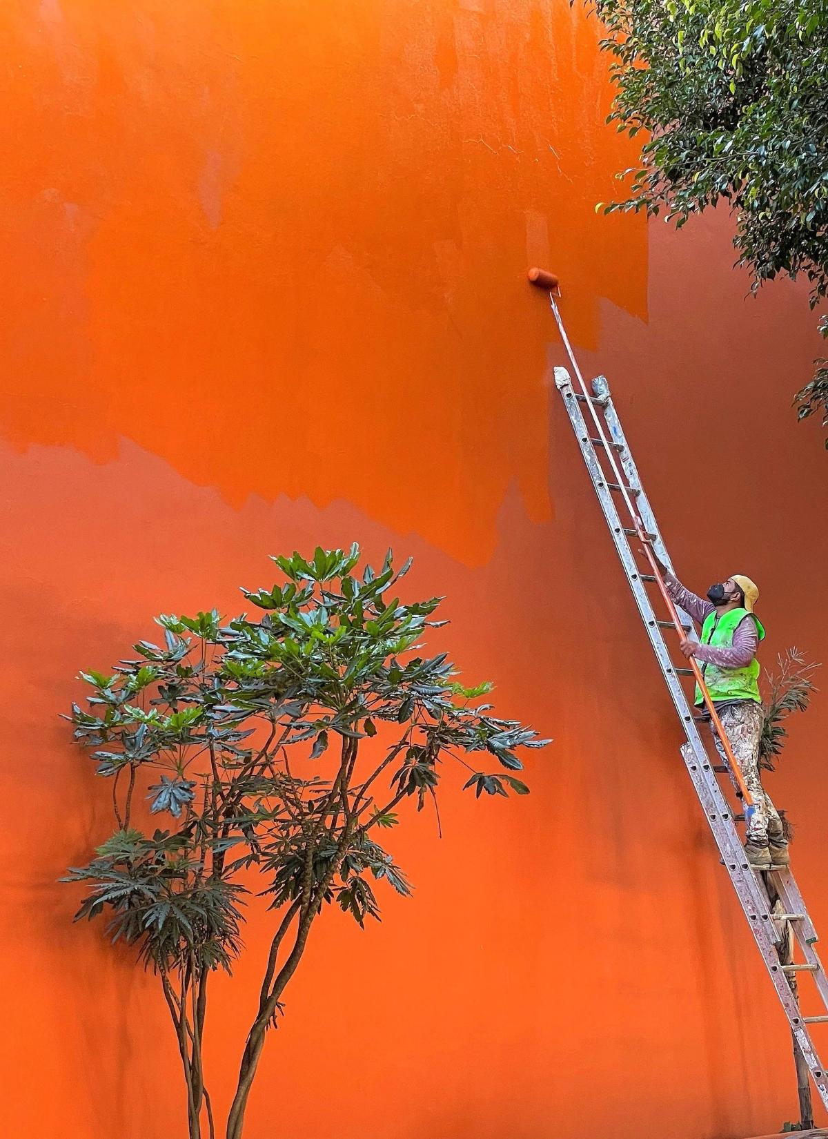 Construction worker painting wall orange