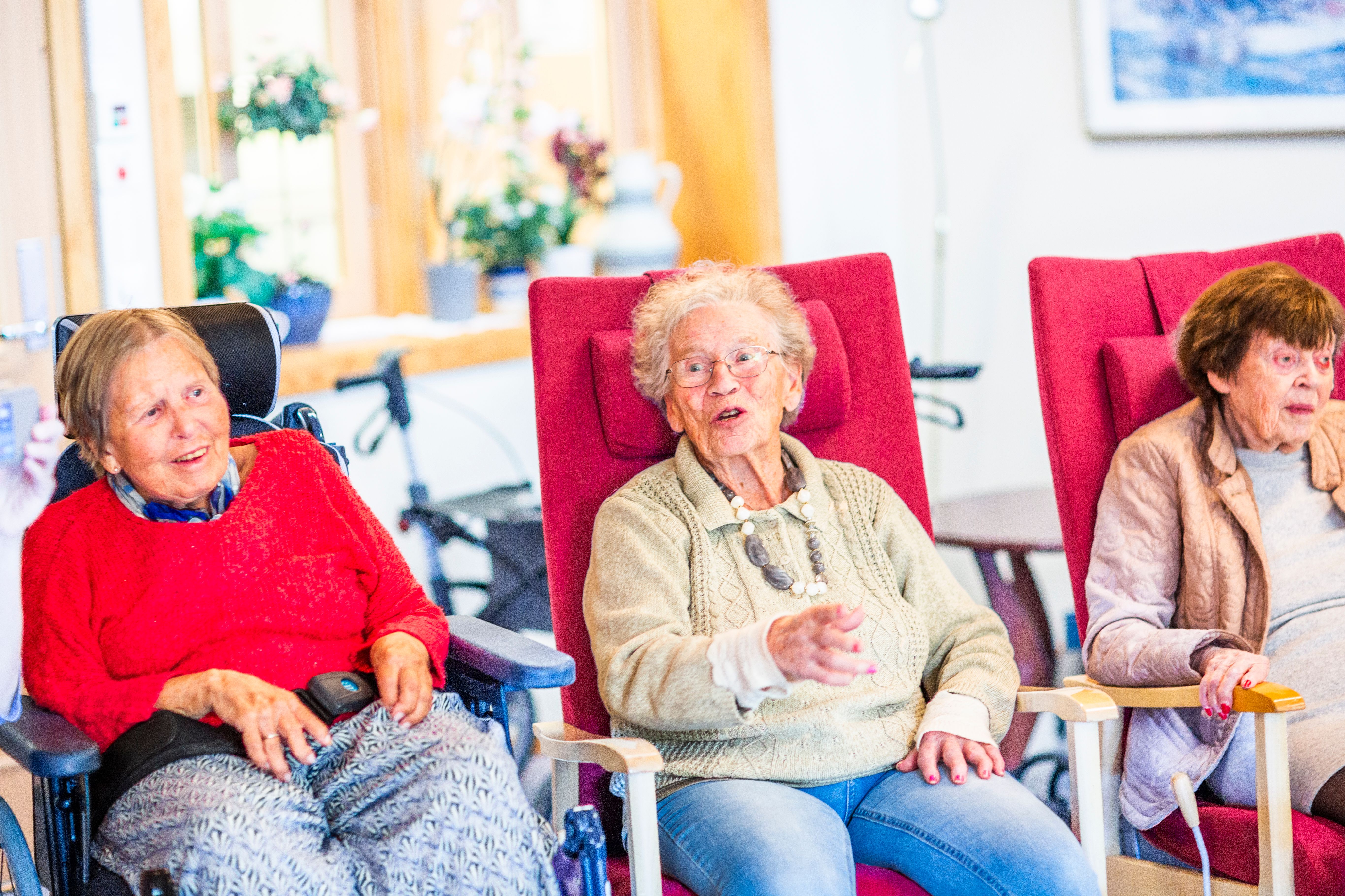 Eldre kvinner synger sammen på eldreinstitusjon.