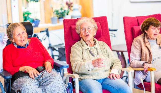 Eldre kvinner synger sammen på eldreinstitusjon.