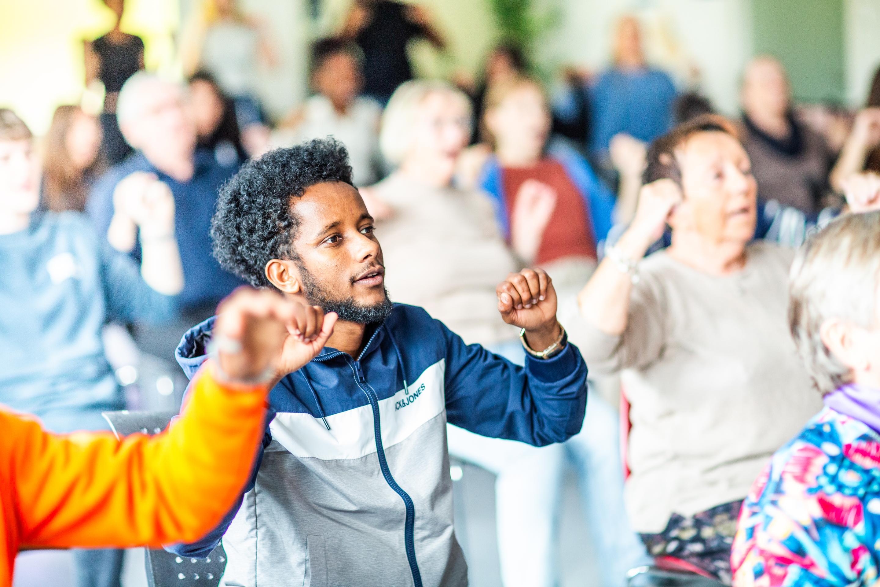 Elev ved Fyllingsdalen vgs. synger sammen med pensjonister og klassekamerater i klasserommet.