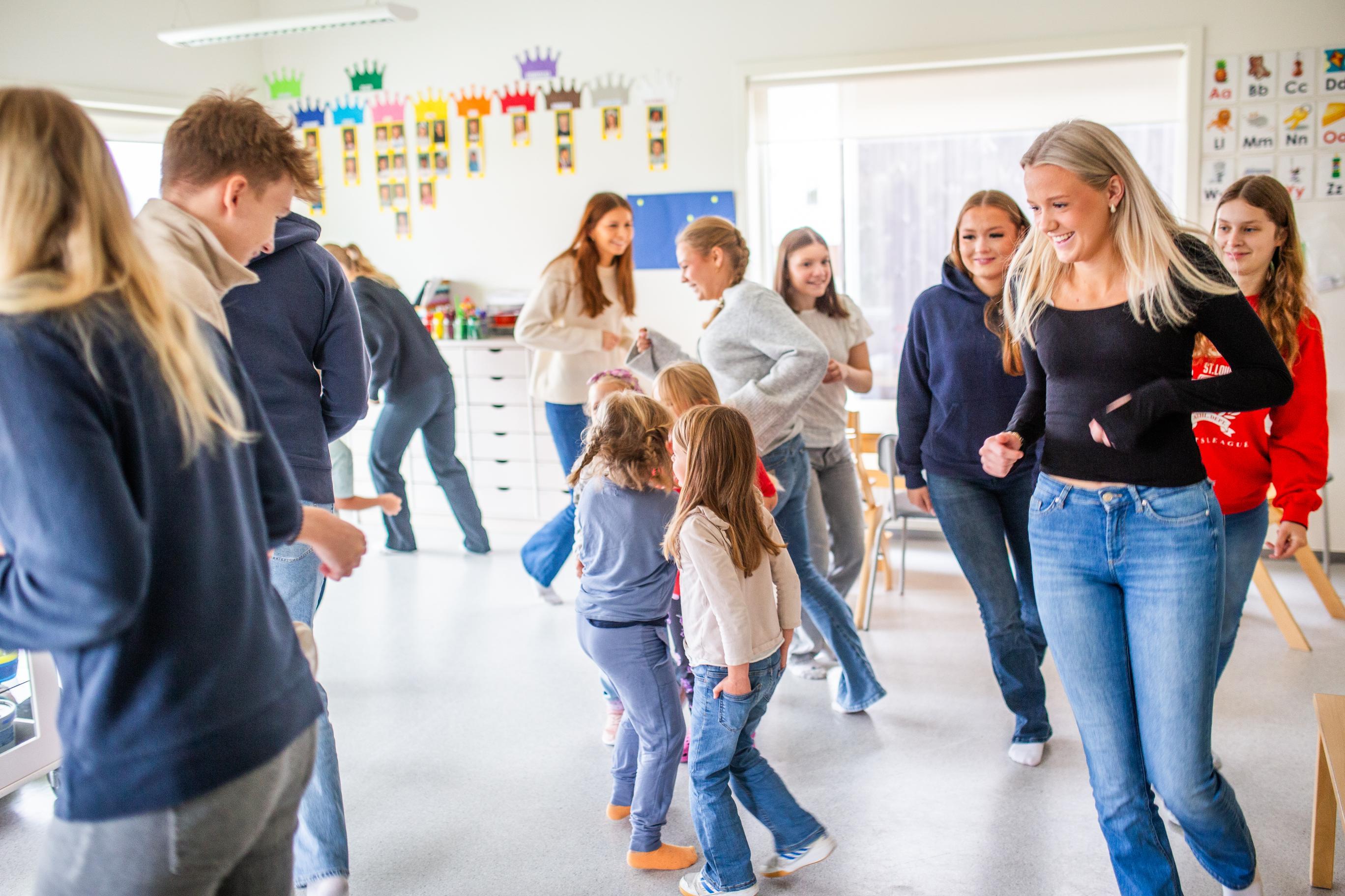 VGS-elever synger og danser sammen med barn i barnehage.
