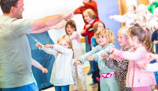Mannlig lærer synger sammen med barn i grunnskolen.