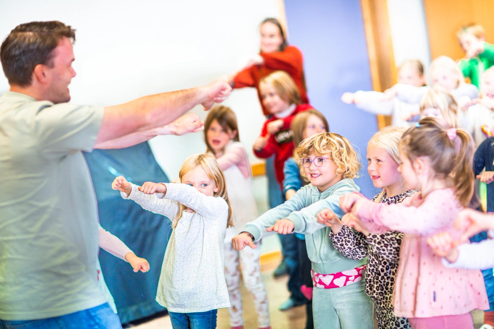 Mannlig lærer synger sammen med barn i grunnskolen.