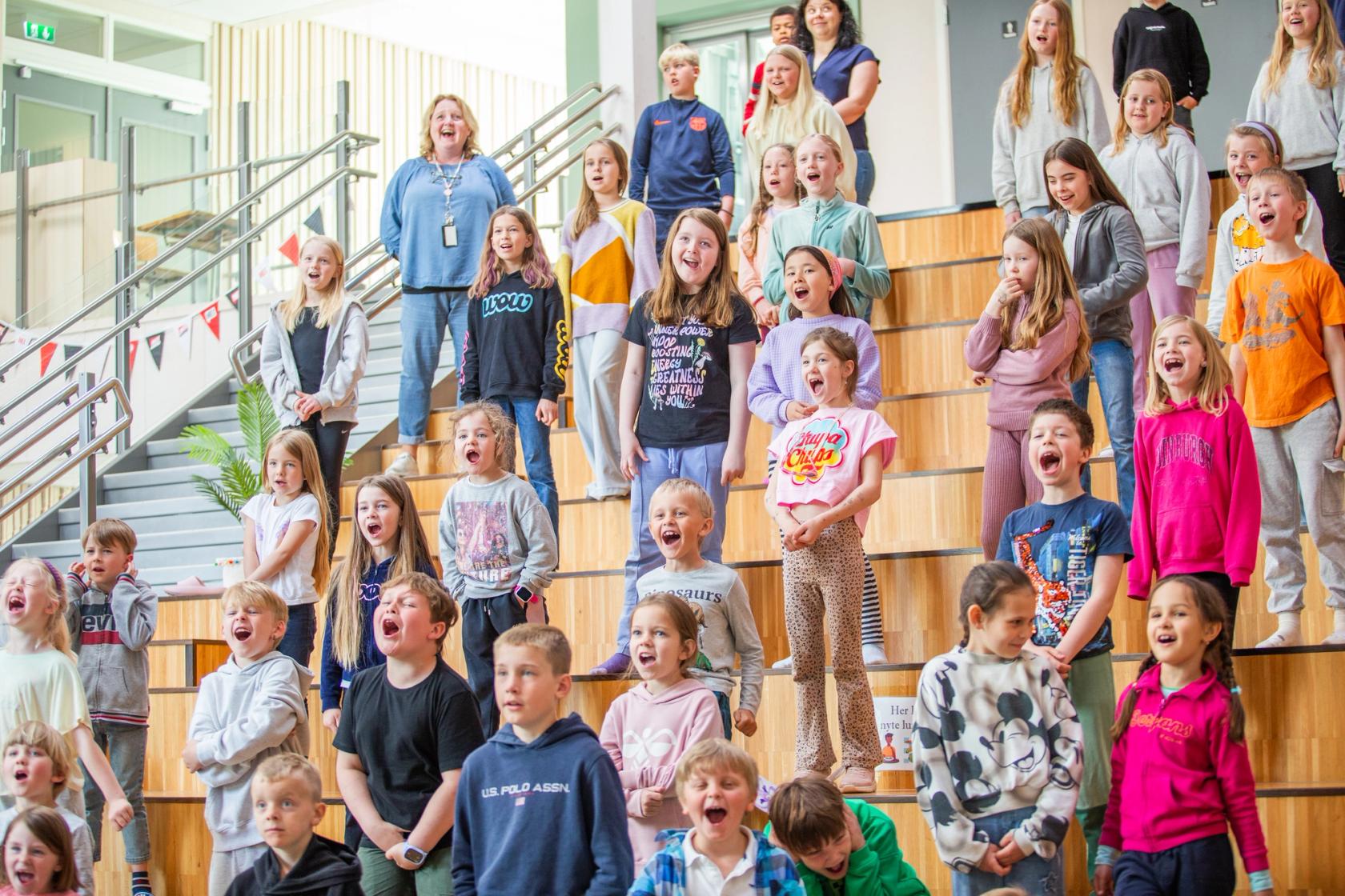 Barn synger for full hals i skolens allrom under Skolenes sangdag 2024 på Eikefjord barne og ungdomskule.