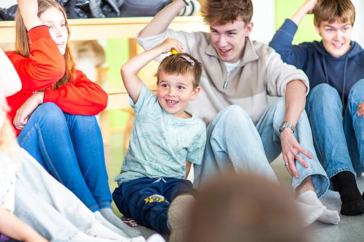 Barnehagebarn og VGS-elever møtes for en felle sangstund der de eldste får øve på rollene som voksenpersoner ute i felten.