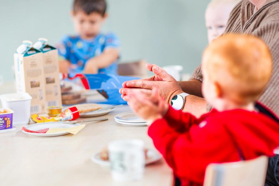 Barn og ansatte sitter klar ved matbordet.