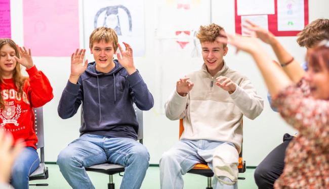 Elever synger sammen i sirkel mens de øver på å synge sammen med barnehagebarn.