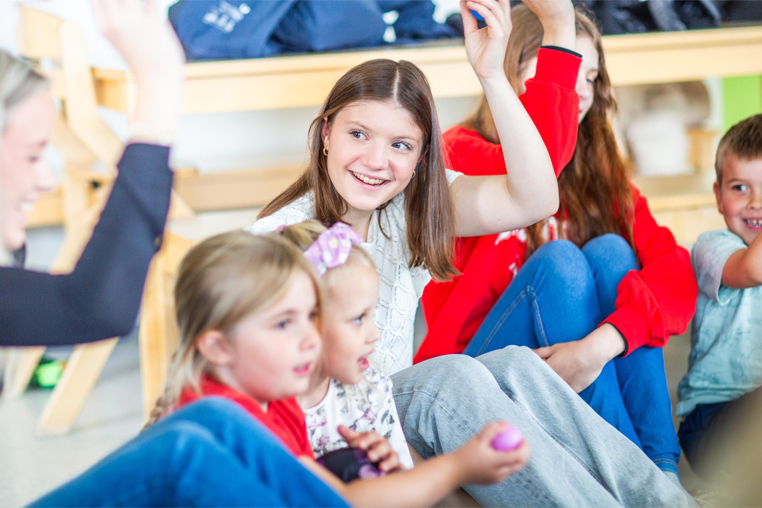 Elever synger sammen i sirkel mens de øver på å synge sammen med barnehagebarn.