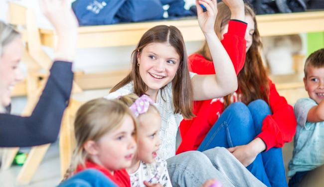 Elever synger sammen i sirkel mens de øver på å synge sammen med barnehagebarn.