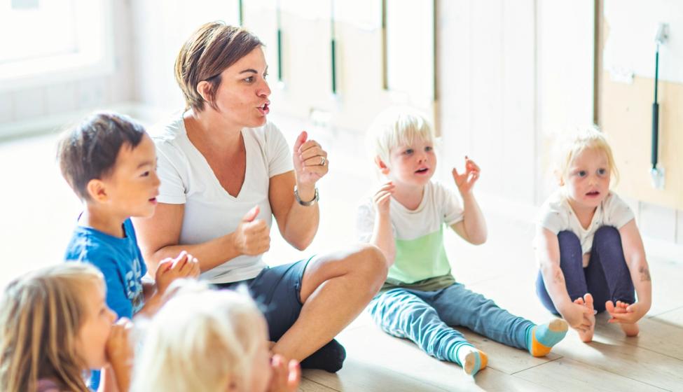 Barn i en Syngende barnehage som synger sammen med en ansatt.