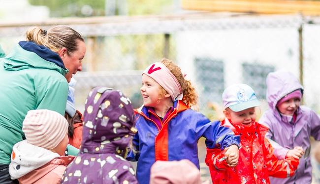 Ansatt synger sammen med barn under et måltid i barnehagen.