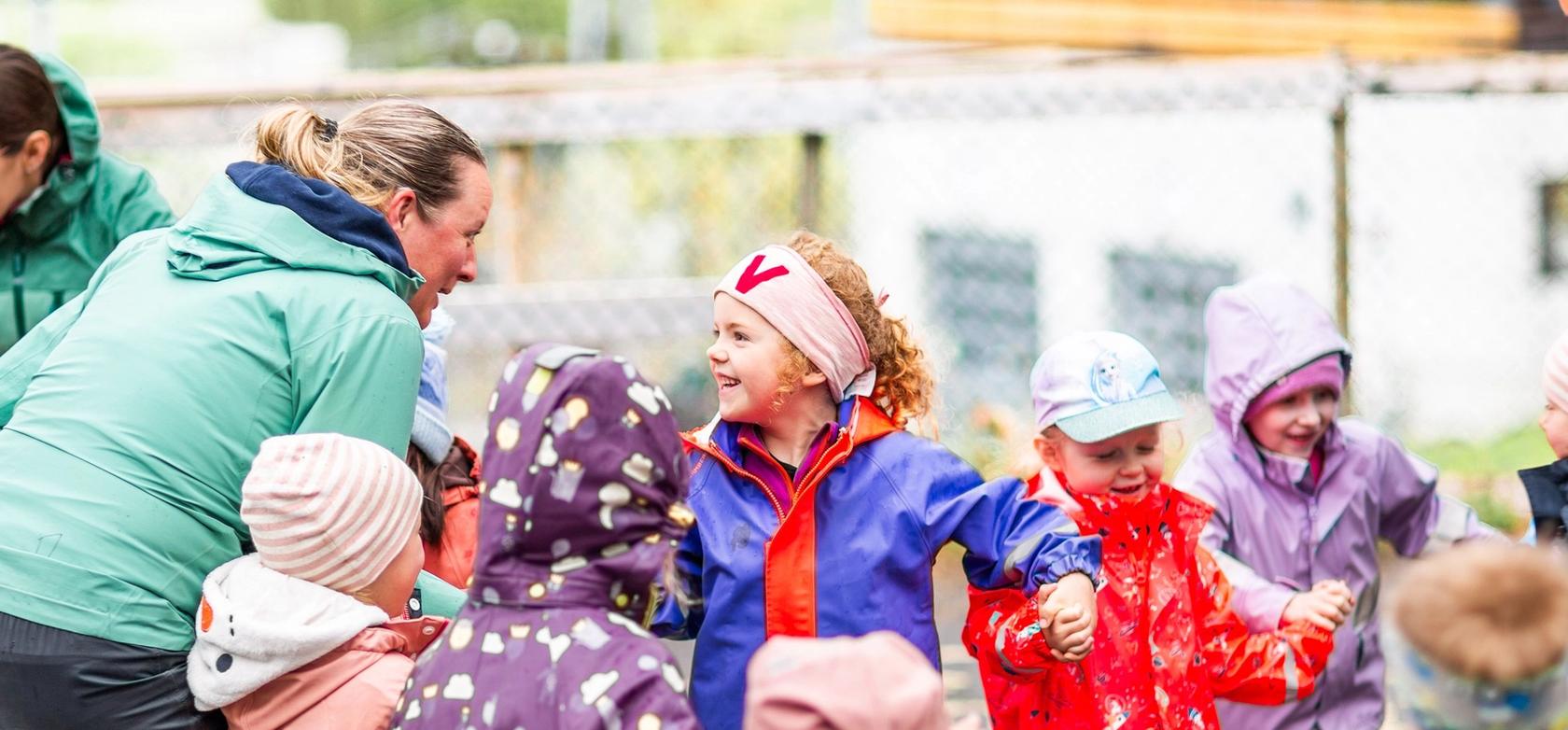 Ansatt synger sammen med barn under et måltid i barnehagen.
