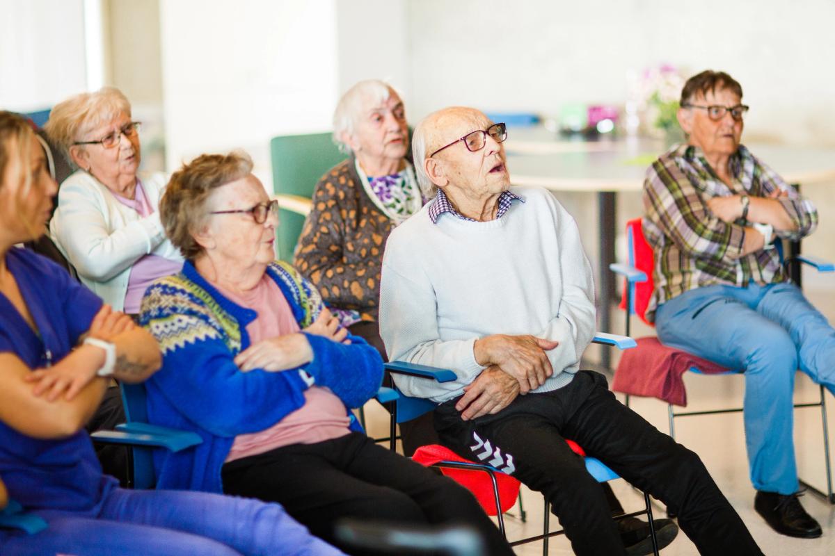 Eldre på institusjon synger sammen til allsangstund på skjerm