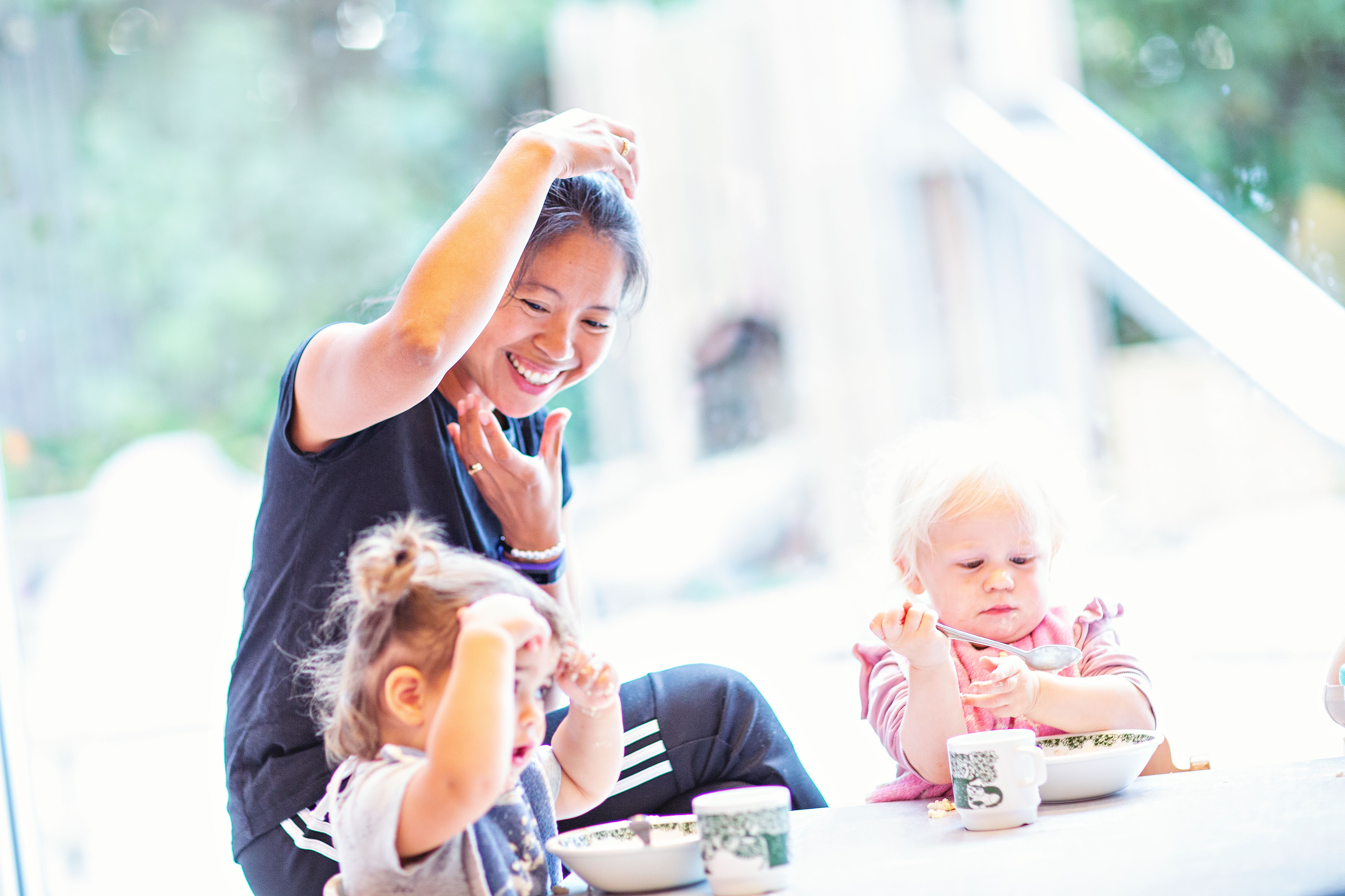 Bilde av en ansatt og to barn som synger ved matbordet