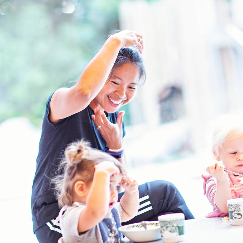 Bilde av en ansatt og to barn som synger ved matbordet