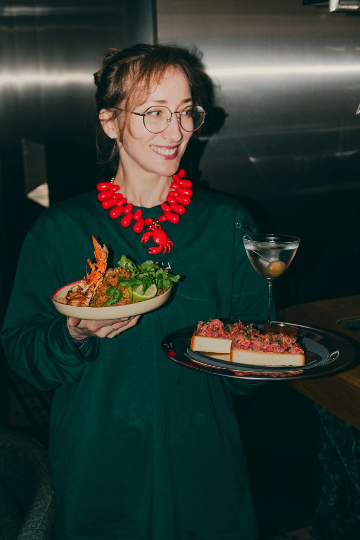 Pinch server holding seafood rice and tuna tartare on toast with a martini at Pinch Lisbon